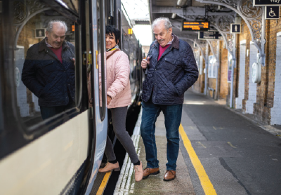 An_older_couple_steps_onto_a_train.png