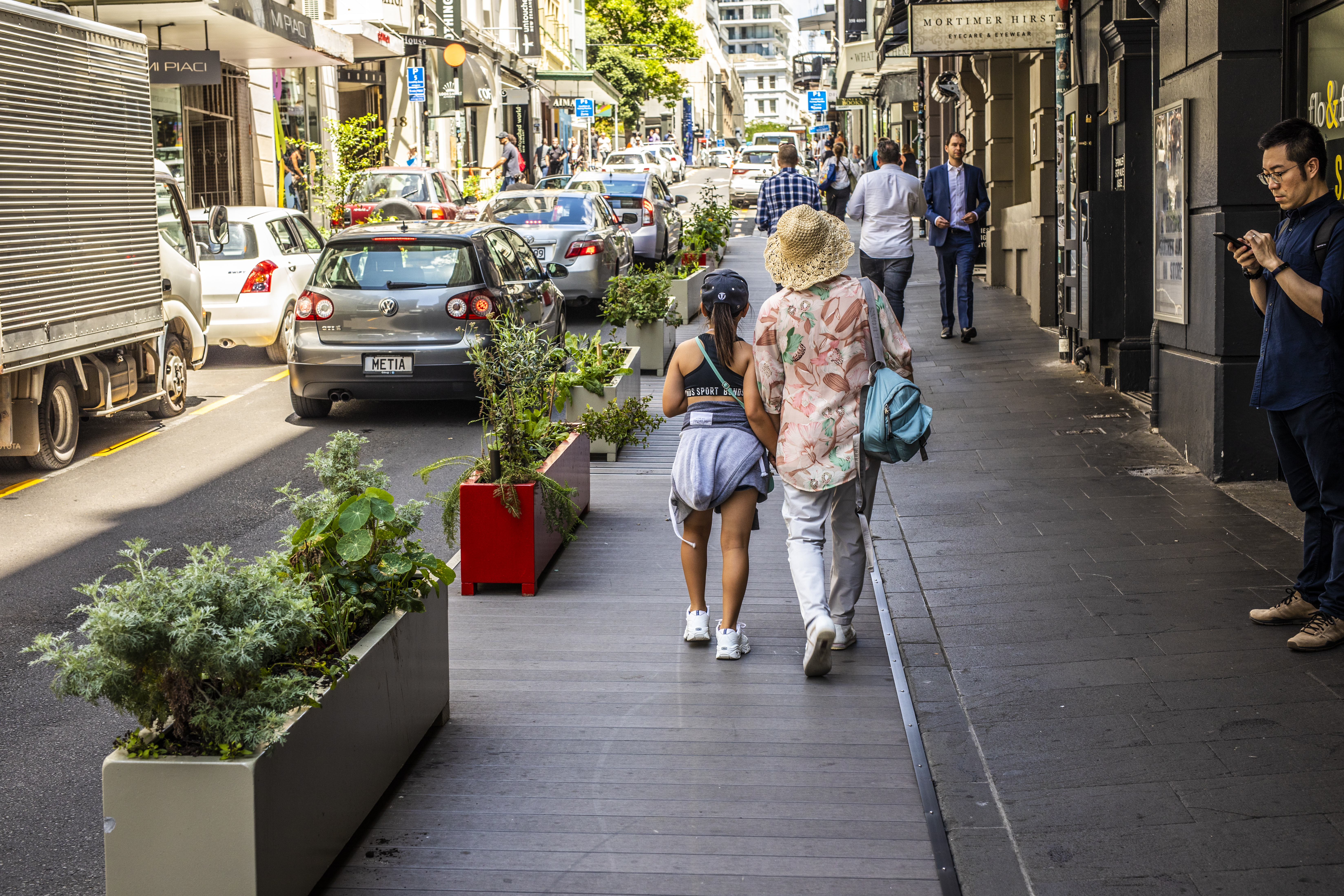 People walking along temporary kerb build outs on High Street